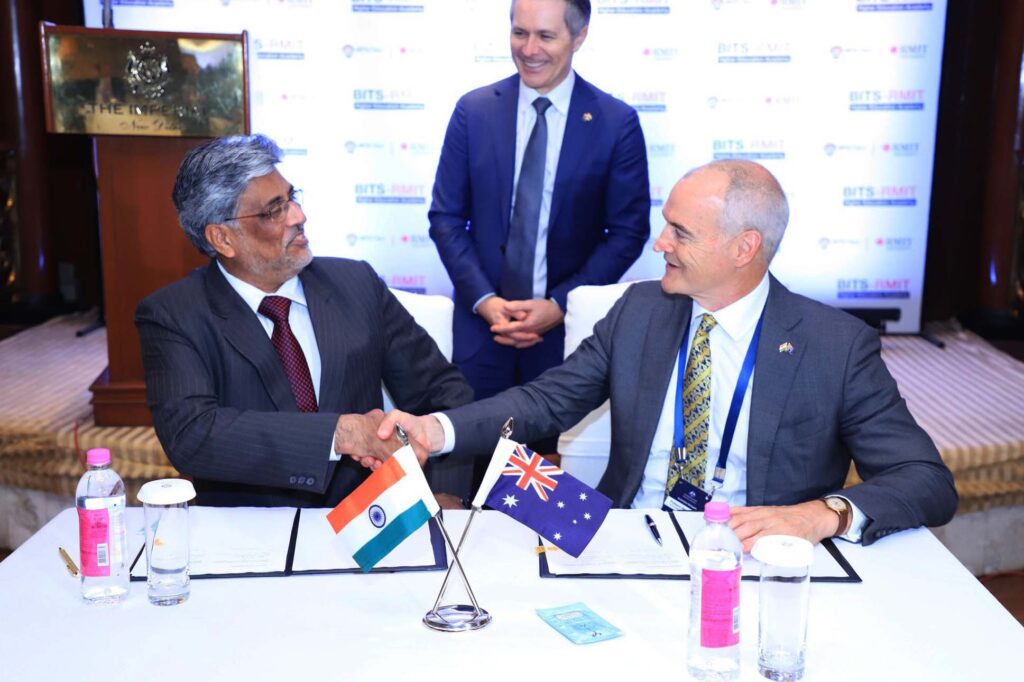 BITS and RMIT leaders seated, shaking hands with the Federal Minister for Education.