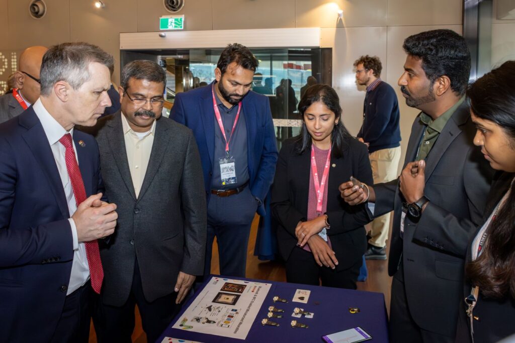 Indian and Federal Education Ministers with four others standing around a table examining items at RMIT.